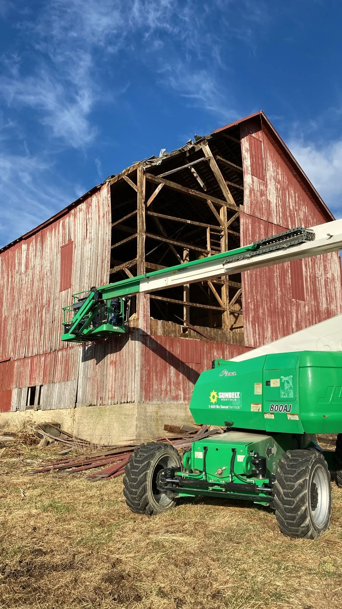Crew re-siding a red barn from a boom lift