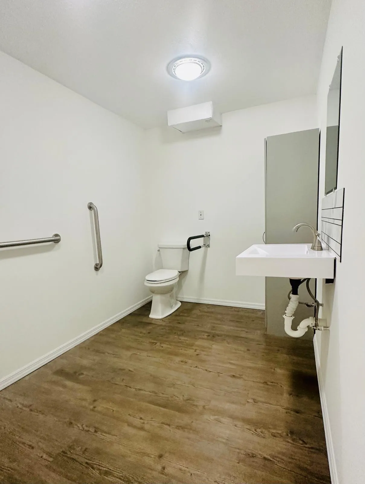 Accessible bathroom remodel with grab bars, wall-hung sink and new floor