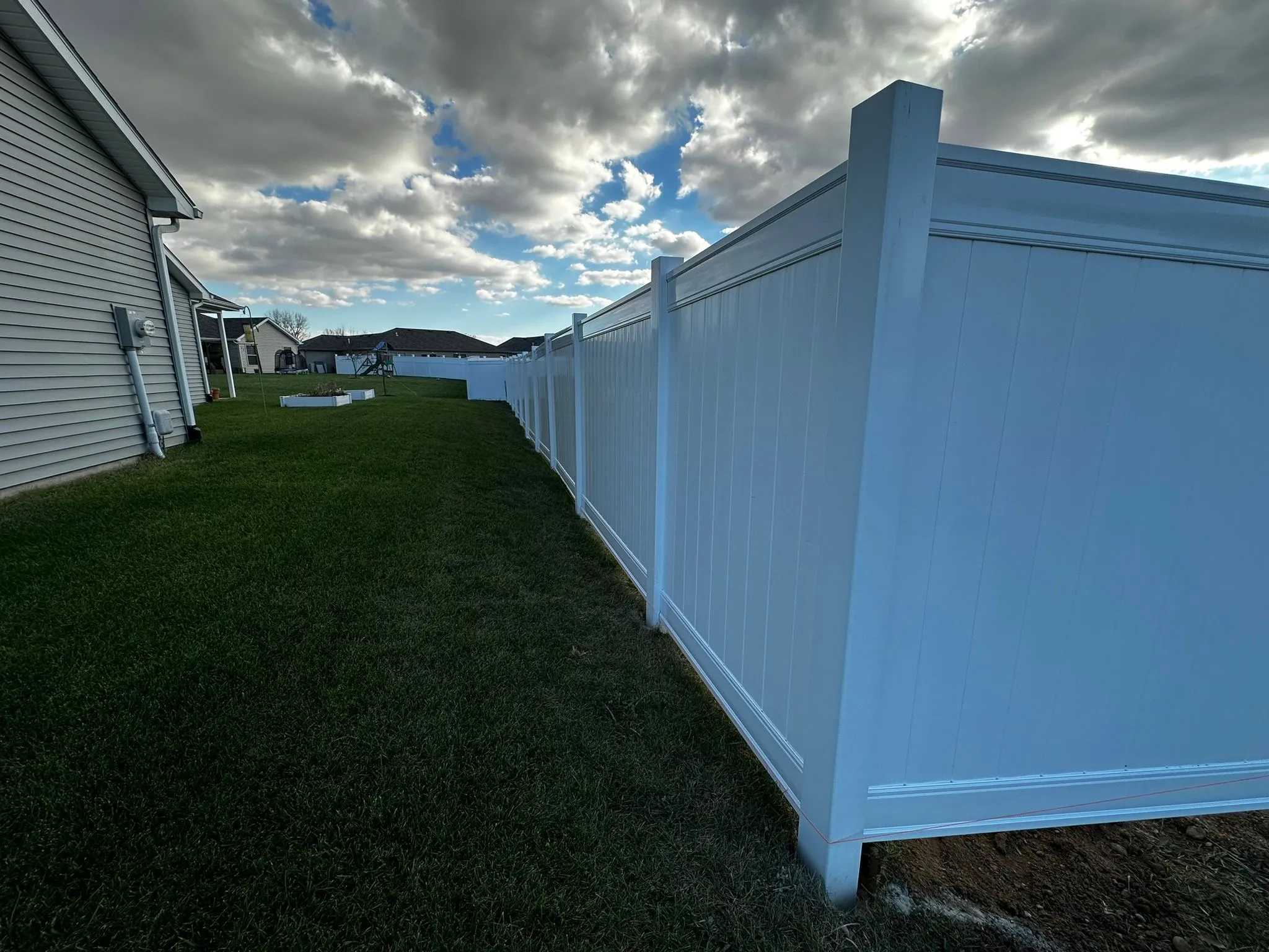New white vinyl privacy fence installed along a backyard
