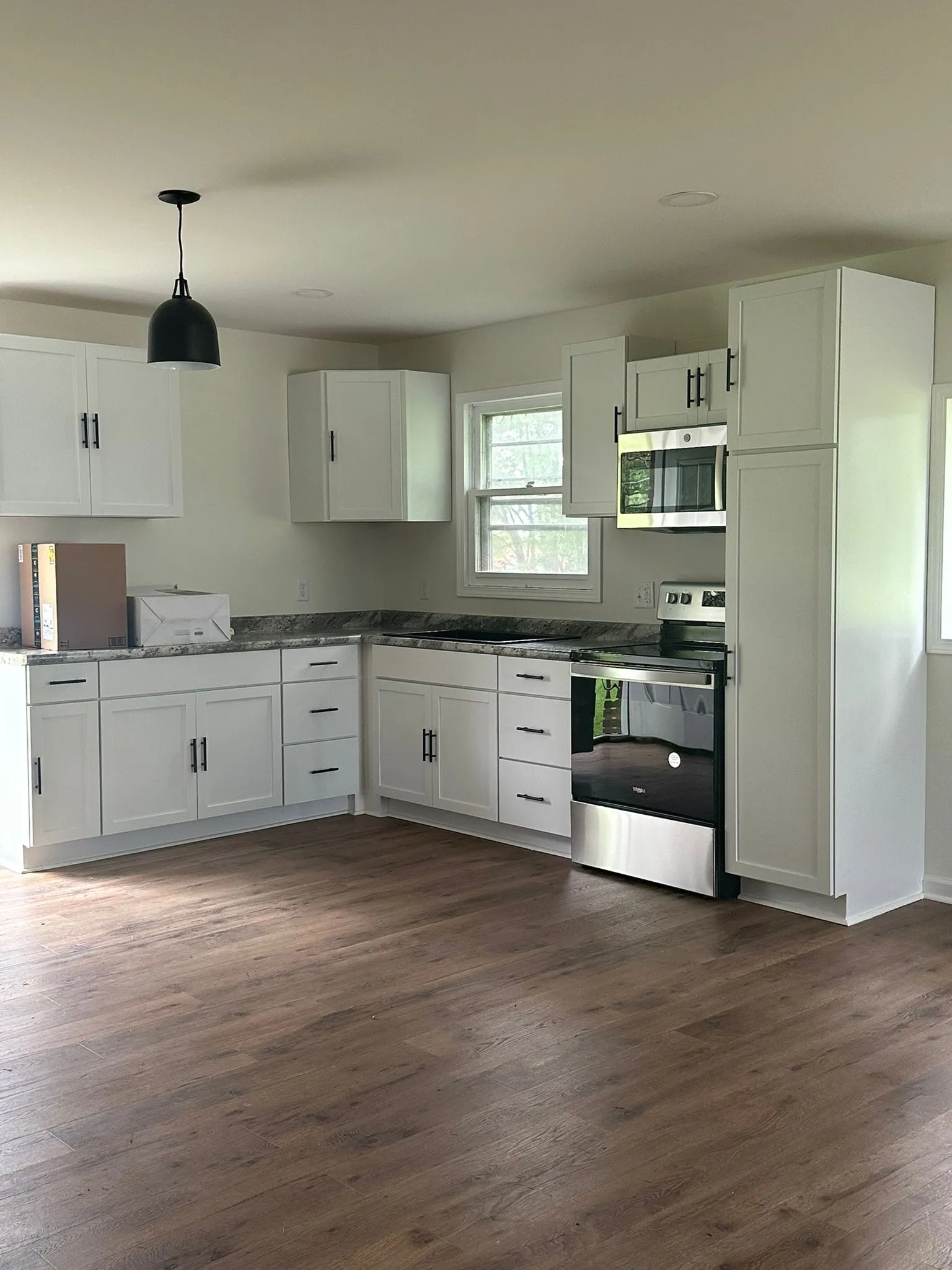 Finished kitchen with white shaker cabinets, stainless appliances and new vinyl plank flooring