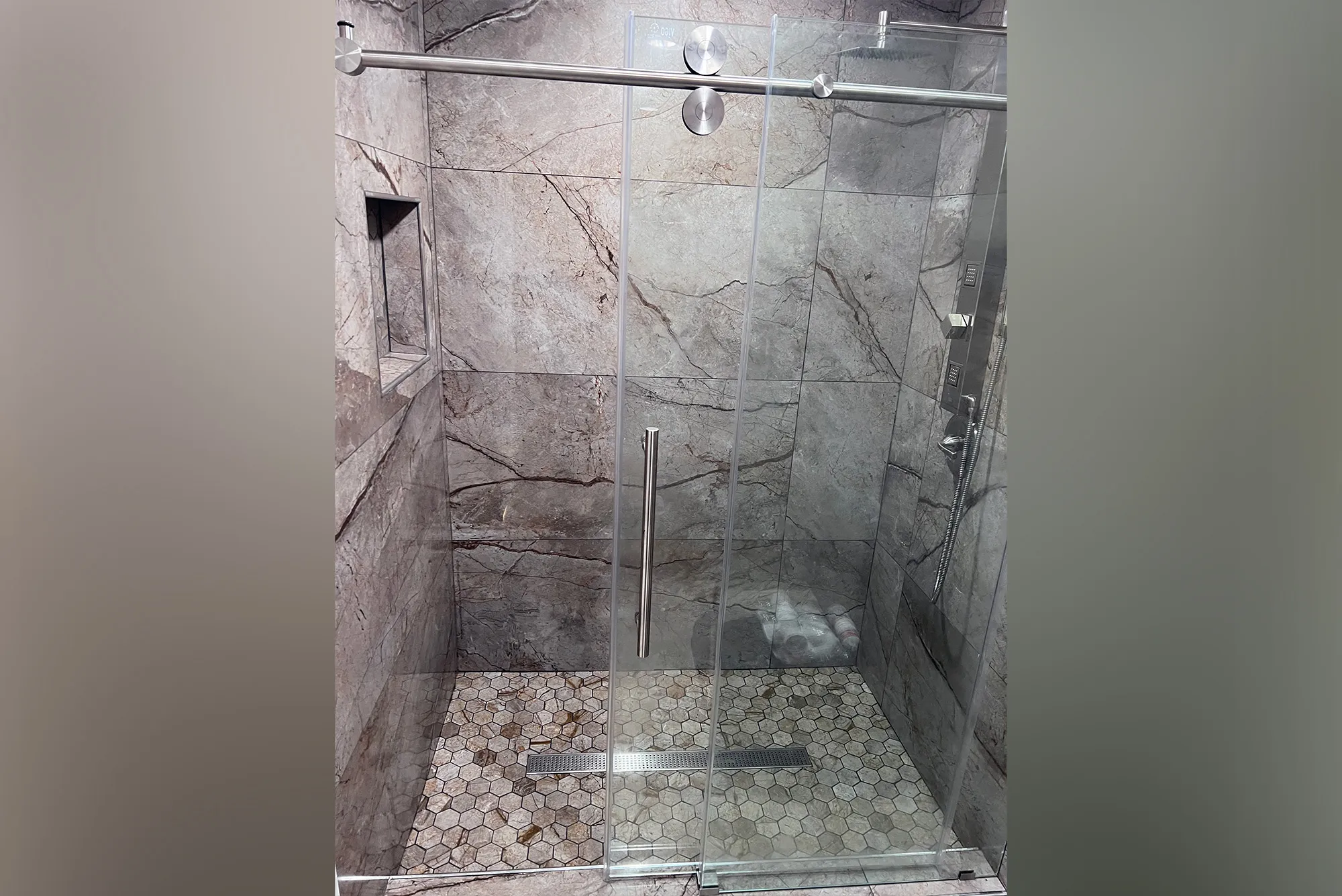 Walk-in shower with gray marble-look tile and sliding glass door